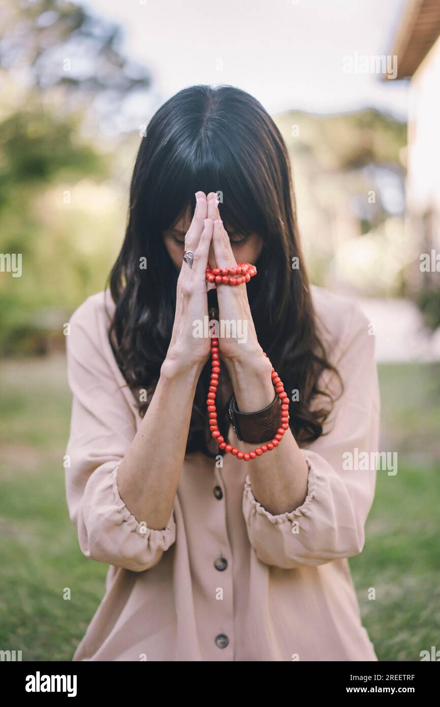 Une femme consciente se tient la main dans une position de namaste tout en pratiquant la respiration sur son arrière-cour Banque D'Images