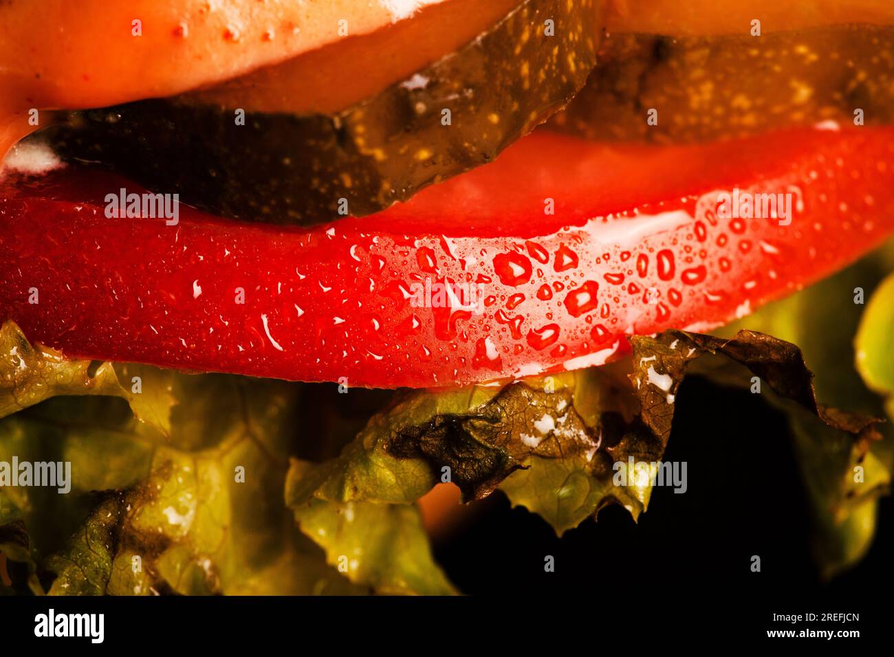 Gros plan sur des gouttes d'eau de hamburger abstingrer sur une tomate rouge Banque D'Images