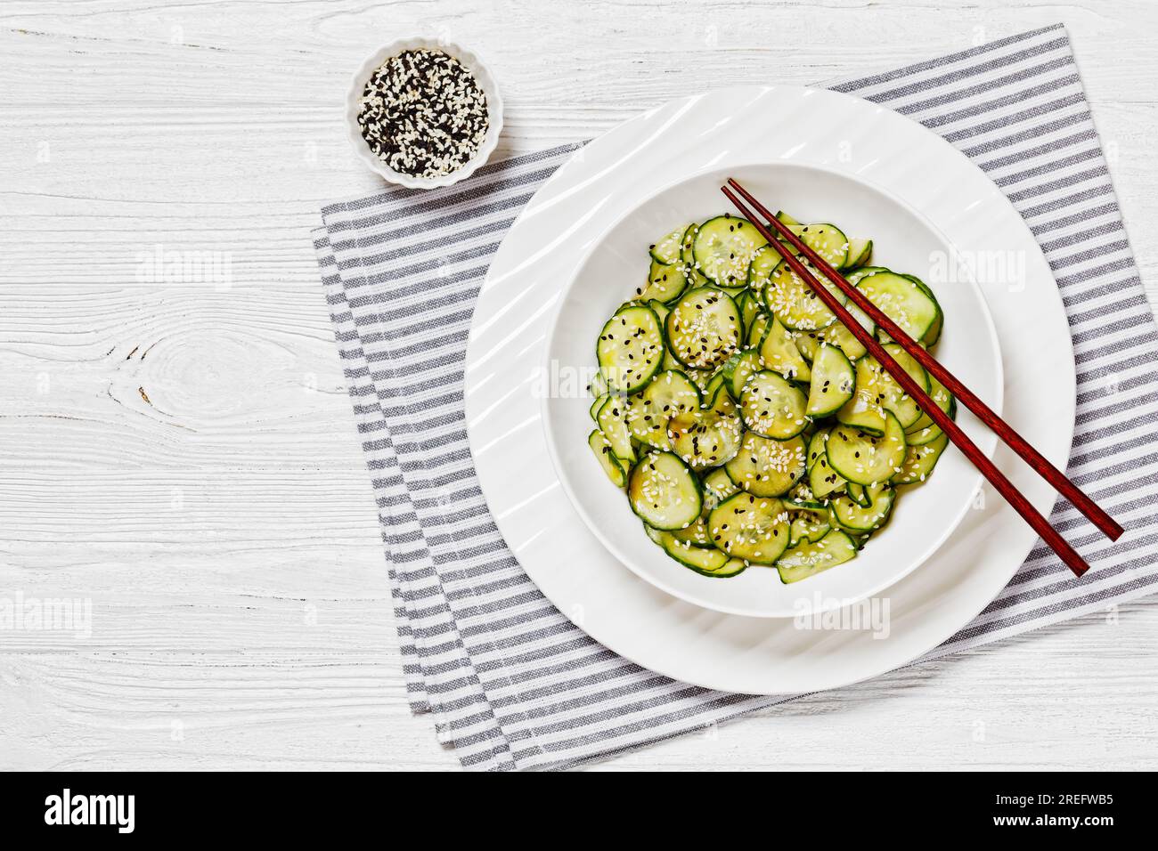 Sunomono, salade japonaise de concombres, tranches de concombres avec sauce asiatique de soja, vinaigre de riz, huile de sésame et sucre dans un bol blanc avec baguettes Banque D'Images