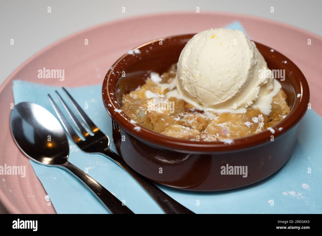 une boule de glace à la vanille servie sur une pâte à biscuits chaude servie dans un bol rouge foncé sur une assiette rose. Banque D'Images