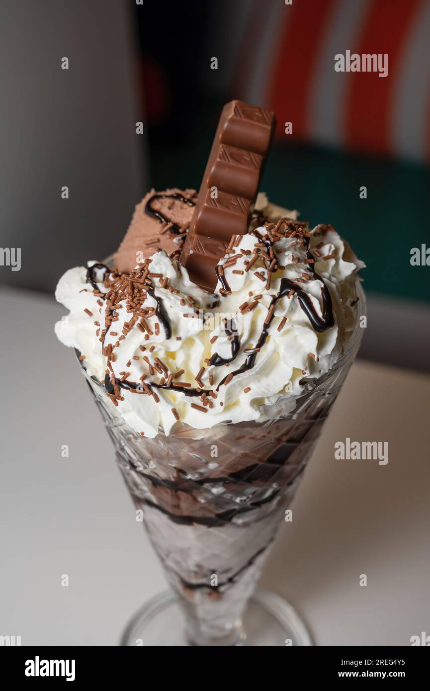 Sundae glacé au chocolat servi dans un grand verre à sundae avec 3 boules de crème glacée, ainsi qu'une variété de sauces et garnitures. Banque D'Images