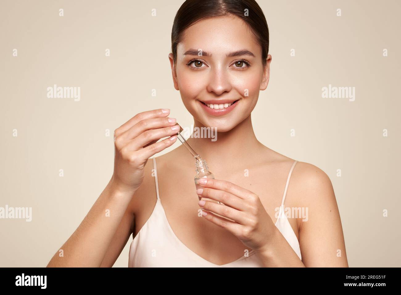 Belle femme élégante tenant un pot cosmétique de sérum d'huile ou d'acide hyaluronique dans sa main. Peau du visage parfaite Banque D'Images