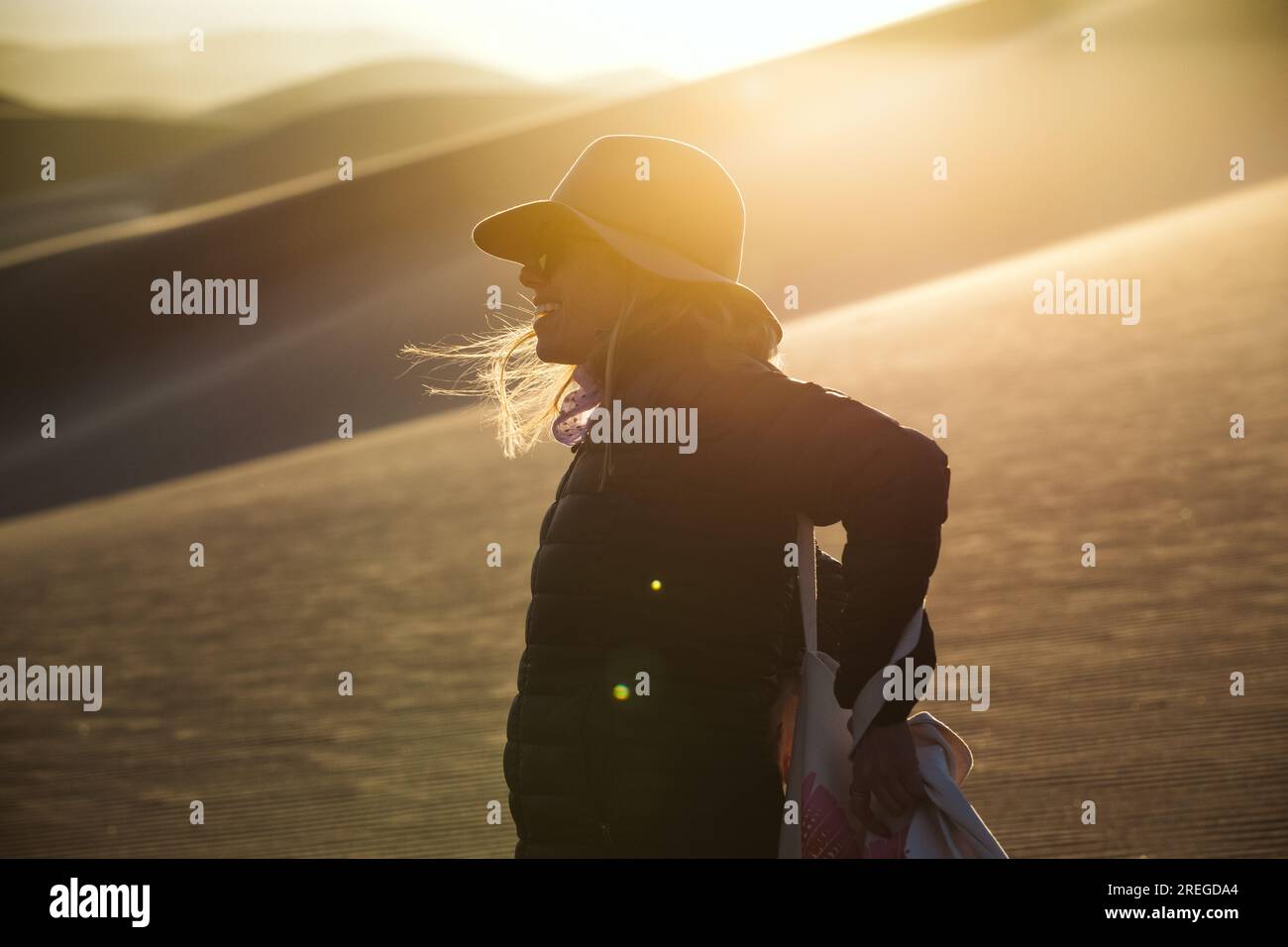 portrait de profil d'une aventurière féminine en chapeau de feutre au coucher du soleil dans les dunes Banque D'Images