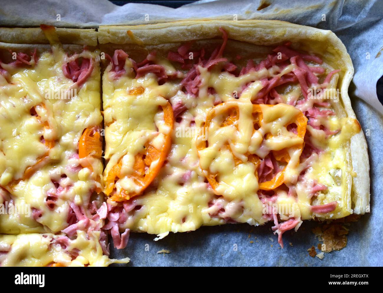 Pizza maison avec de la viande et des tomates jaunes sur une plaque de cuisson Banque D'Images