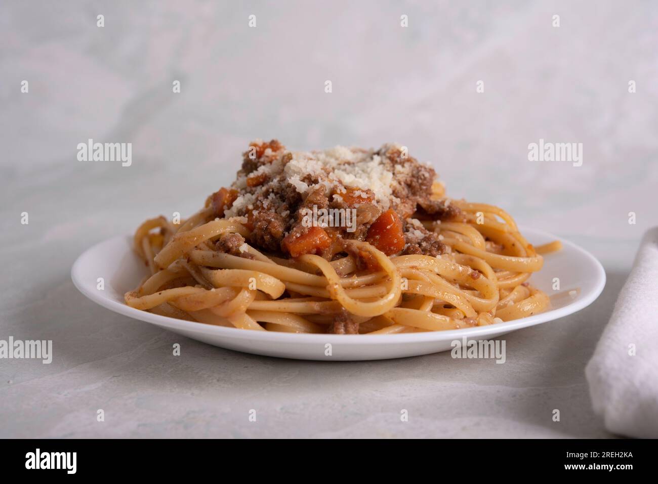 Assiette blanche de pâtes alla bolognaise avec sauce à la viande, fromage et légumes Banque D'Images