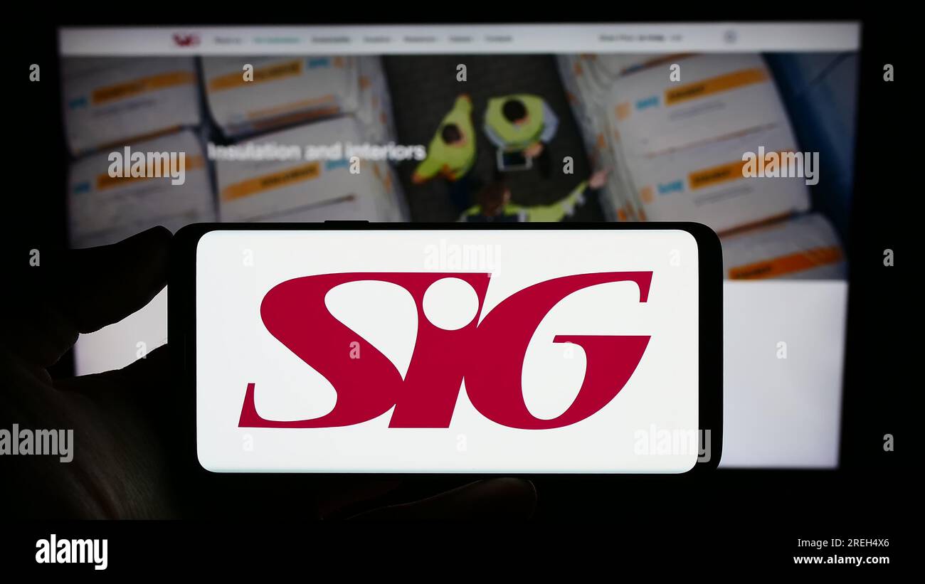 Personne tenant un smartphone avec le logo de la société britannique de matériaux de construction SIG plc sur l'écran devant le site Web. Concentrez-vous sur l'affichage du téléphone. Banque D'Images