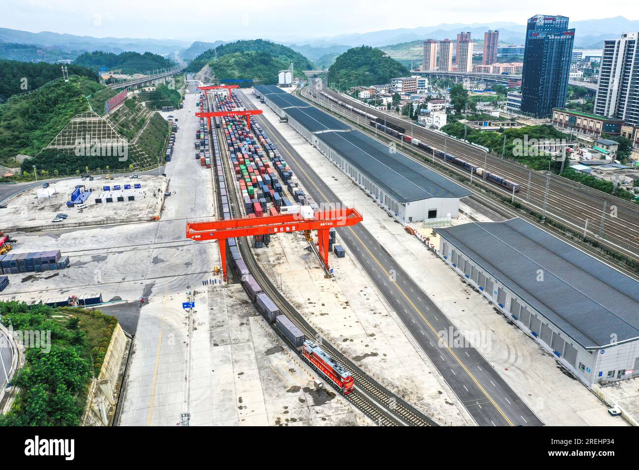 (230728) -- GUIYANG, 28 juillet 2023 (Xinhua) -- cette photo aérienne prise le 28 juillet 2023 montre le premier train de marchandises direct Chine-Asie centrale depuis le port logistique international terre-mer de Dulaying quittant la gare de Dulaying à Guiyang, dans la province du Guizhou, dans le sud-ouest de la Chine. Un train de marchandises a quitté vendredi le port logistique international terre-mer de Dulaying pour Almaty au Kazakhstan, marquant le lancement du premier service de train de marchandises intermodal direct rail-route Chine-Asie centrale au départ de Guiyang. Environ 1 300 tonnes de produits agricoles seront transportées du Kazakhstan à Guiyang sur le trajet de retour Banque D'Images