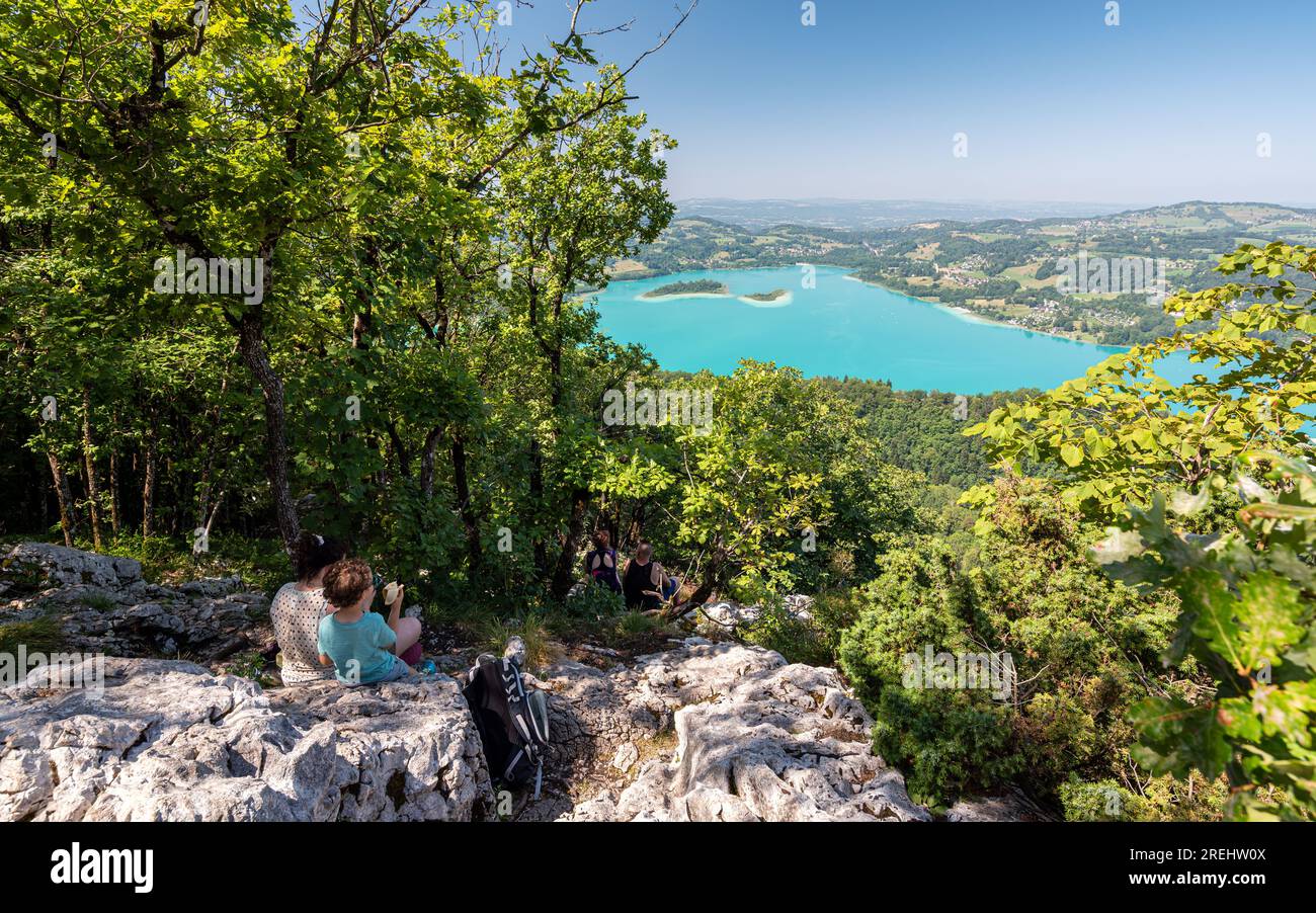 Randonneurs déjeunant sur les rochers, contemplant le lac d'Aiguebelette d'un point de vue, un lac naturel connu pour sa couleur bleu-vert. Banque D'Images