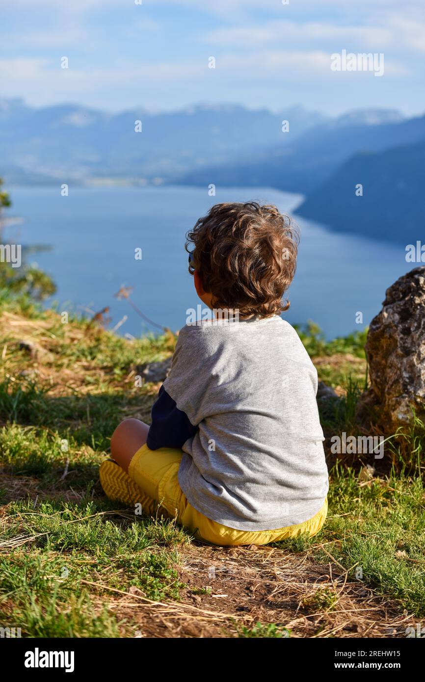 Enfant vu de derrière contemplant d'un point de vue élevé le lac du Bourget ('Lac du Bourget' en français) entouré de montagnes dans le département Banque D'Images