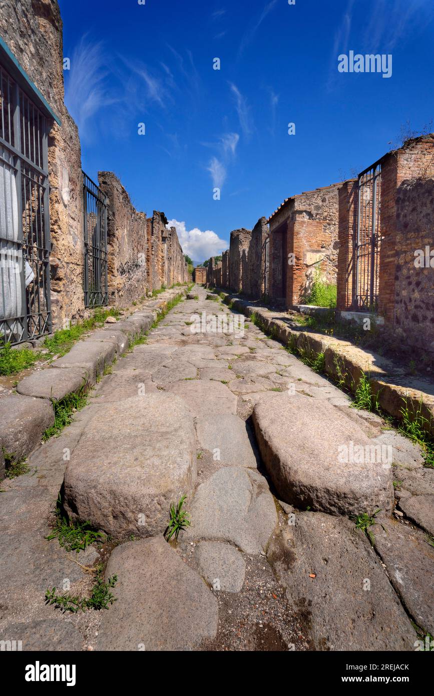 Rue pavée de pierre dans les ruines de l'ancienne ville romaine de Pompéi près de Naples, Italie, détruite par le volcan Vésuve en 79 après JC. Image en perspective profonde Banque D'Images Rue pavée de pierre dans les ruines de l'ancienne ville romaine de Pompéi près de Naples, Italie, détruite par le volcan Vésuve en 79 après JC. Image en perspective profonde Banque D'Images