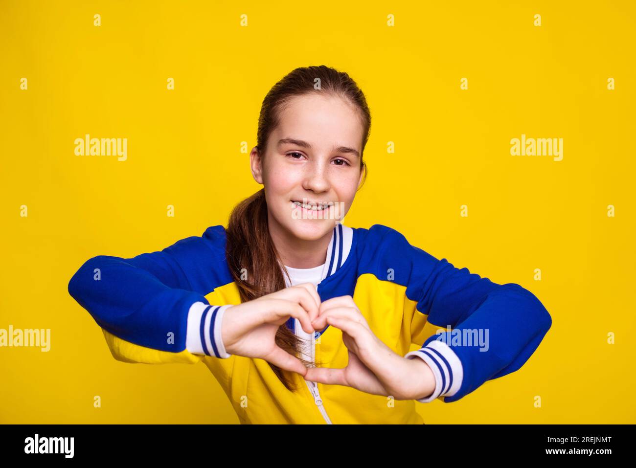 sport préféré, entraînement et mode de vie sain, adolescente montre le geste de cœur sur fond jaune Banque D'Images