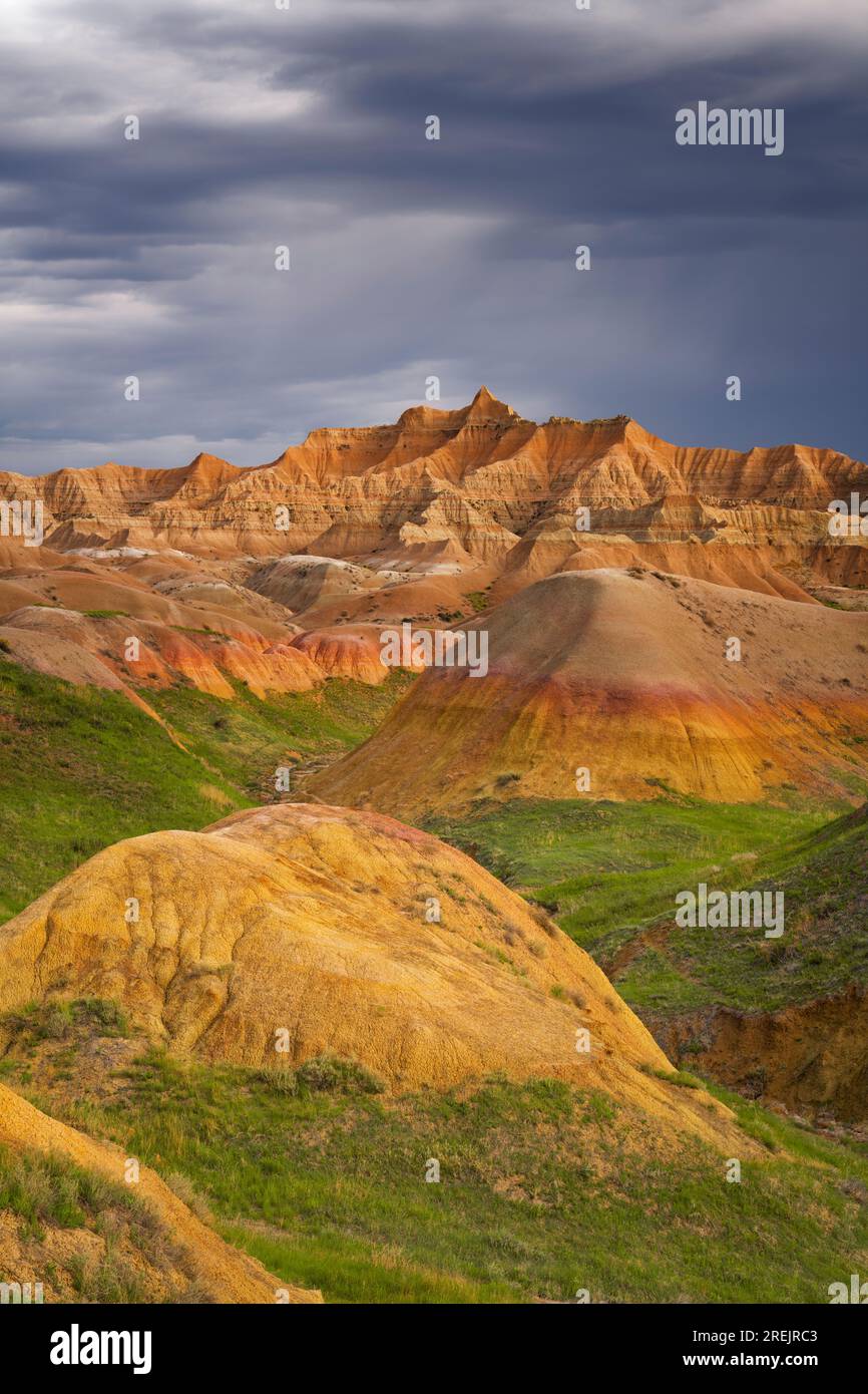 La chaleur des rayons de soleil du soir sur les monts jaunes bien nommés alors que les orages s'accumulent sur les sommets érodés du parc national des Badlands du Dakota du Sud. Banque D'Images