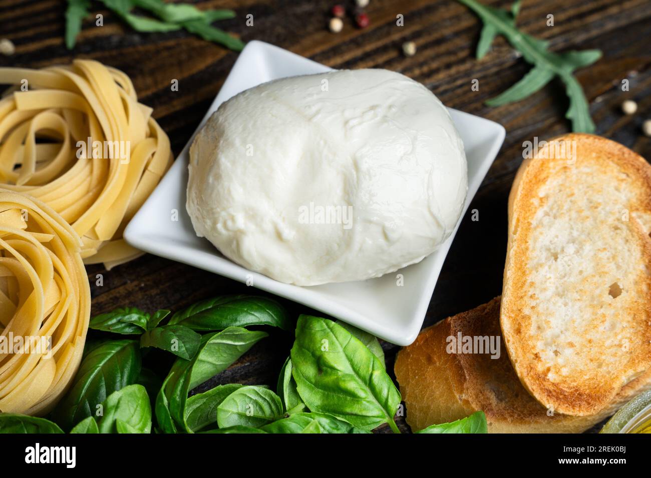 Ingrédients italiens, mozzarella fraîche, bruschetta, tagliatelles crues et feuilles de basilic sur fond en bois foncé Banque D'Images
