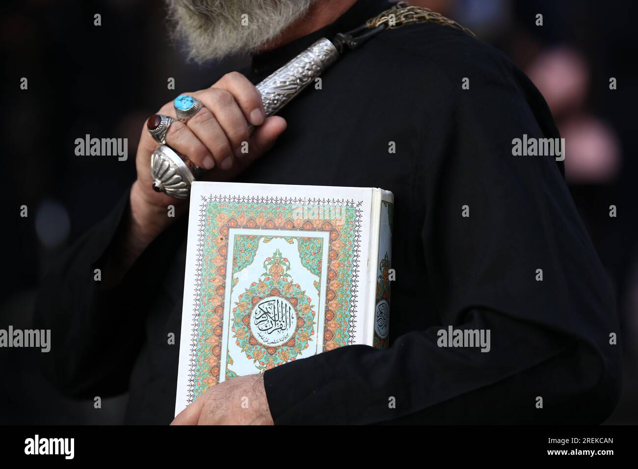 Bagdad, Irak. 28 juillet 2023. Un musulman chiite se bat avec des chaînes  alors qu'il tient une copie du livre sacré le Coran lors d'une cérémonie  rituelle le jour de l'Ashura à