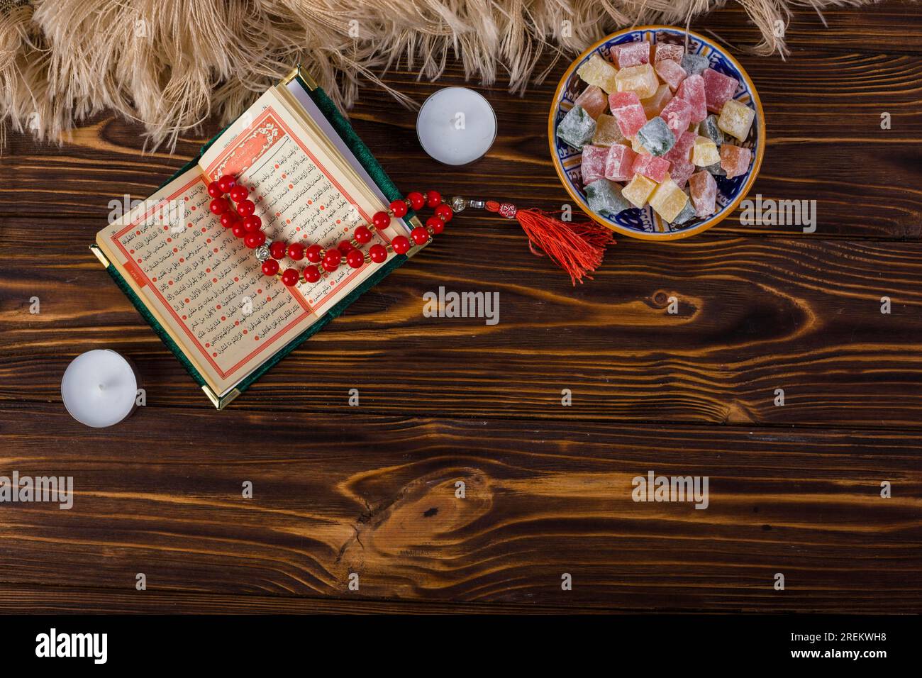 Bol multicolore lukum rouge perles rosaires sacrées kuran avec bougies surface en bois. Belle photo Banque D'Images