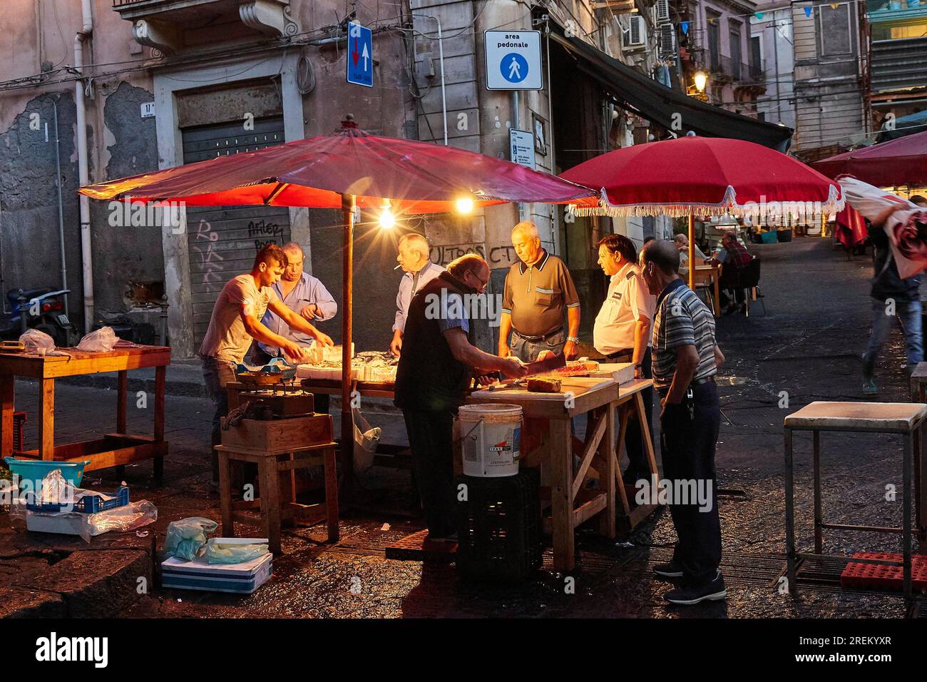 Tôt le matin, marché aux poissons, étal illuminé, vendeur, vieille ville, Catane, côte est, Sicile, Italie Banque D'Images