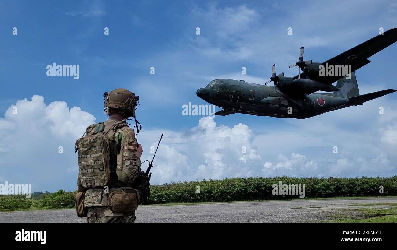 13 juillet 2023 - , Mariannes du Nord - États-Unis Le major Michael Bakke de la Force aérienne du 621e Escadron des opérations de soutien à la mobilité, base interarmées McGuire-dix-Lakehurst, N.J., se prépare alors qu'un C-130 Hercules japonais atterrit sur la zone d'atterrissage Baker à Tinian, aux États-Unis Commonwealth des Mariannes du Nord, 12 juillet 2023. Les membres du 621e Escadron des opérations de soutien à la mobilité, les officiers de liaison de la mobilité aérienne, les membres de l'élément expéditionnaire de liaison aérienne au sol et les capitaines de chargement japonais ont participé à l'exercice Mobility Guardian 23, soutenant la zone d'atterrissage de la coalition, les opérations de la zone de largage et la préparation du fret de soutien Banque D'Images