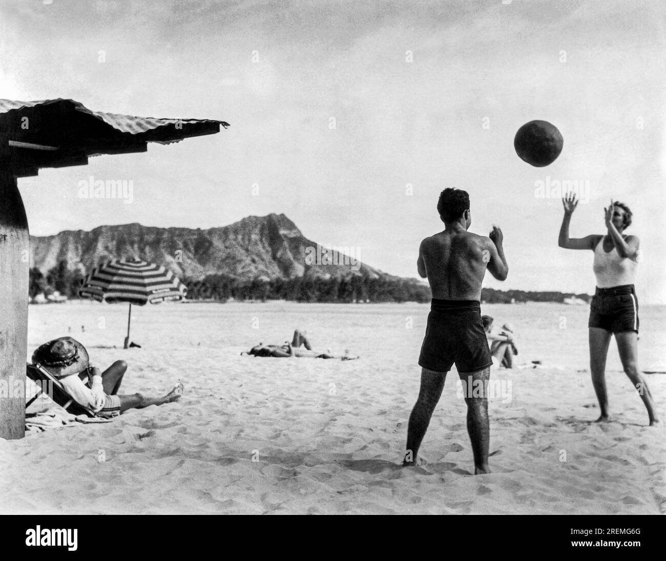 Honolulu, Hawaii : c. 1930 un couple jouant avec un ballon de plage sur Waikiki Beach à Honolulu sur Oahu, avec Diamond Head en arrière-plan. Banque D'Images