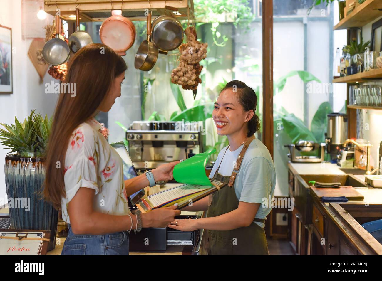 Jeune serveuse vietnamienne travaillant avec la machine de check out et les clients dans le café Banque D'Images