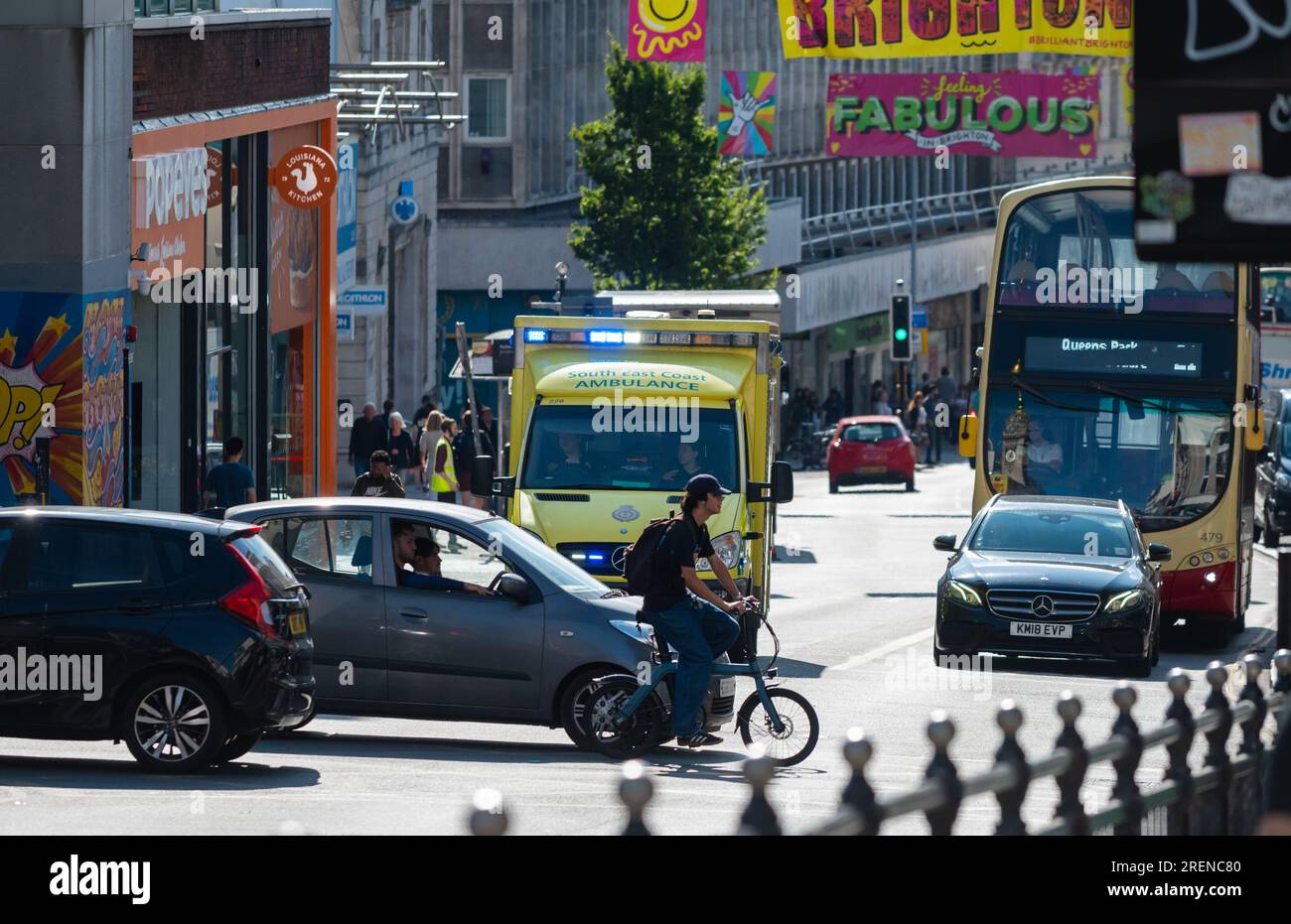 Ambulance d'urgence du NHS dans la circulation dans une ville animée, avec des lumières bleues clignotantes, se rendant à une urgence à Brighton & Hove, Angleterre, Royaume-Uni. Banque D'Images