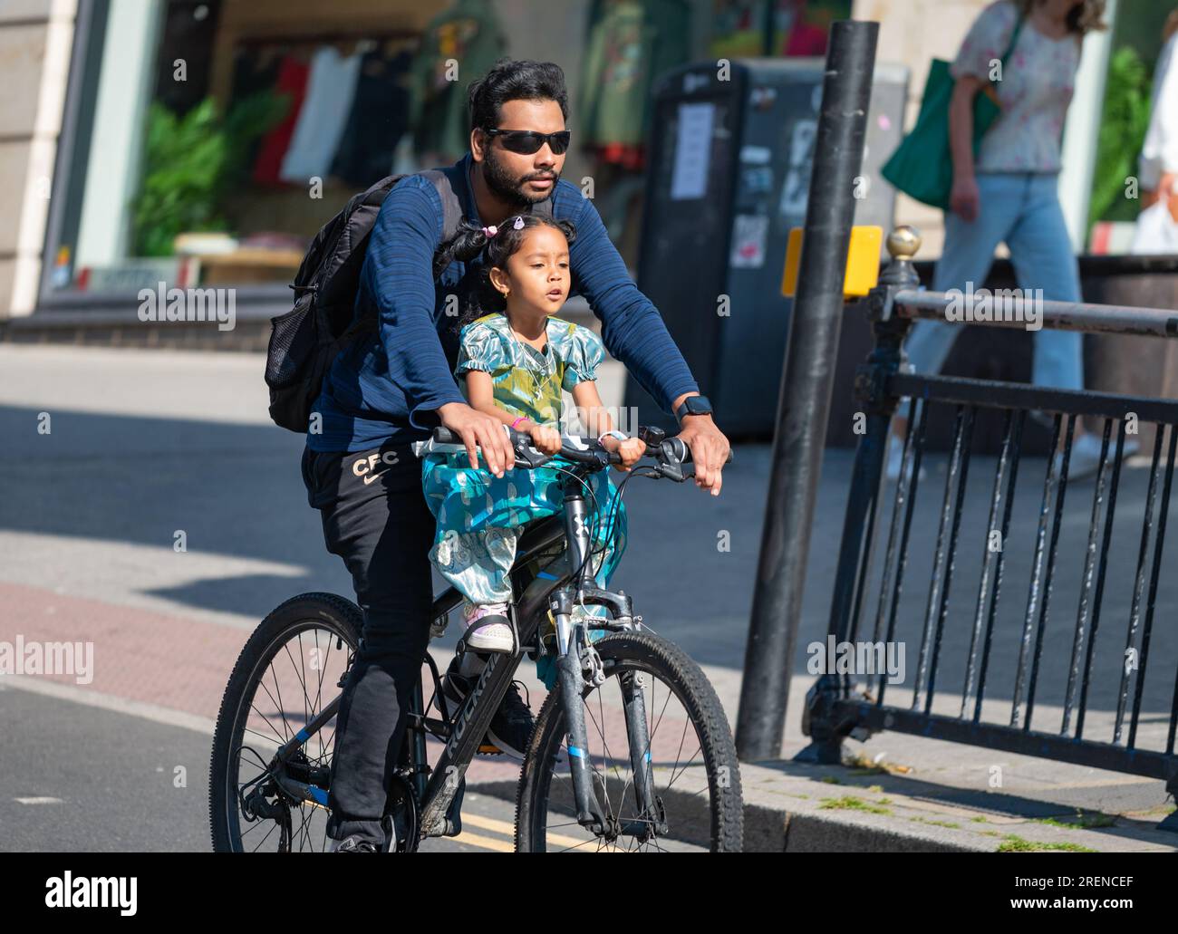Homme et jeune enfant faisant du vélo ensemble sur une route principale, ne portant pas de casques. Cycliste sans casque au Royaume-Uni. Sécurité des enfants. Banque D'Images