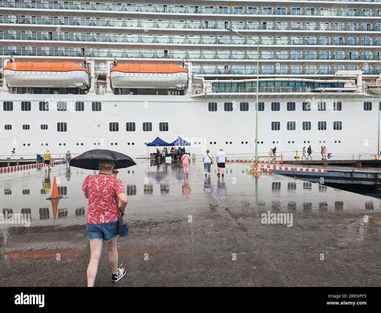 Les gens qui marchent sur le quai vers un grand paquebot britannique de croisière dans les Antilles sous la pluie en janvier 2023 Banque D'Images