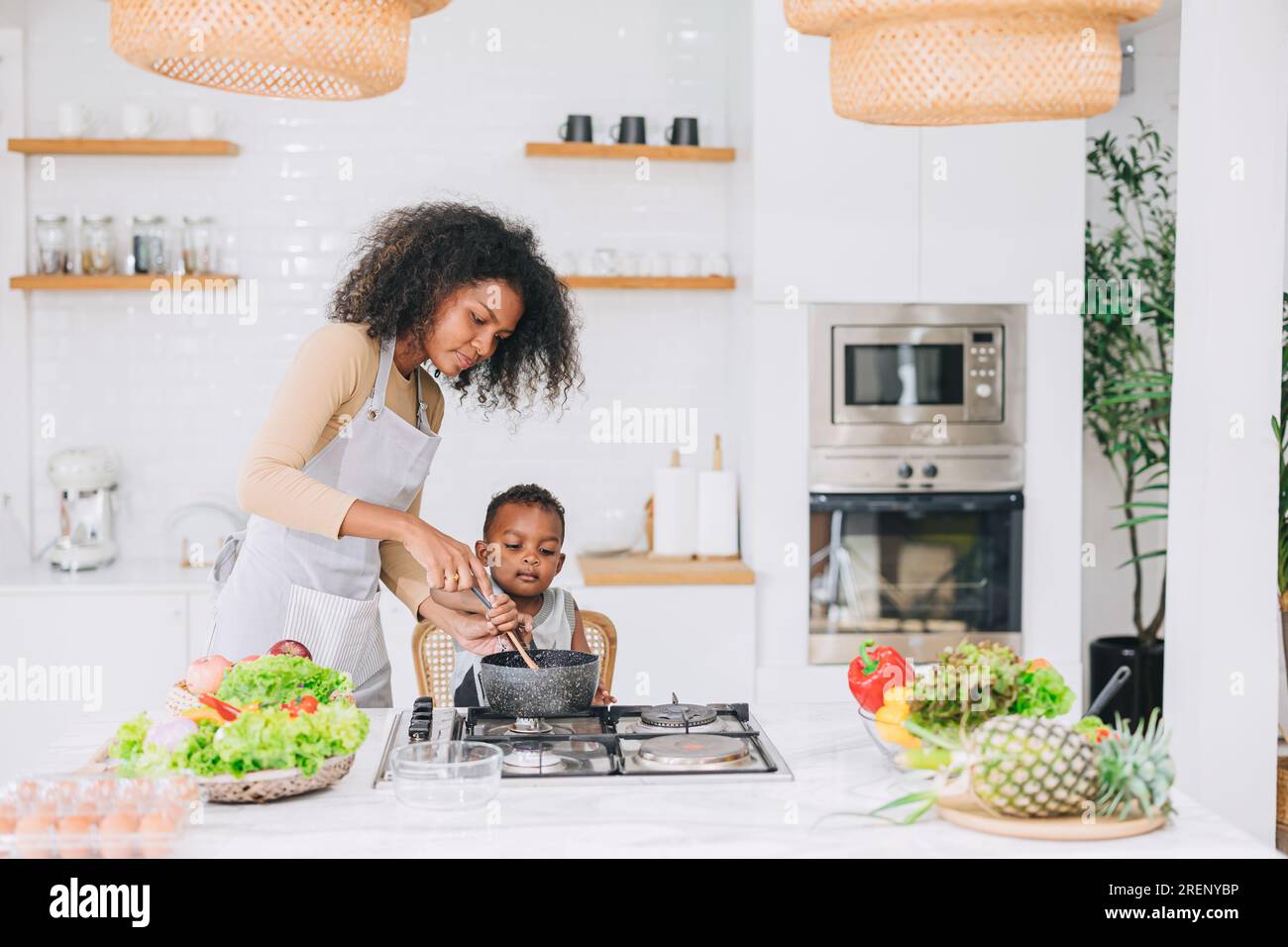 heureuse jeune mère noire africaine avec son garçon belle cuisine mignonne ensemble à l'activité de vacances à la maison Banque D'Images