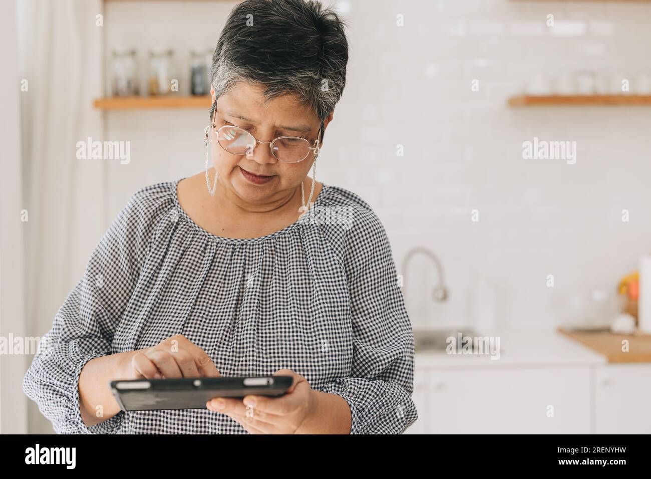 femme asiatique adulte senior apprendre à utiliser le dispositif de technologie moderne. mère essayer de communiquer avec le chat texte de tablette sur l'écran tactile Banque D'Images