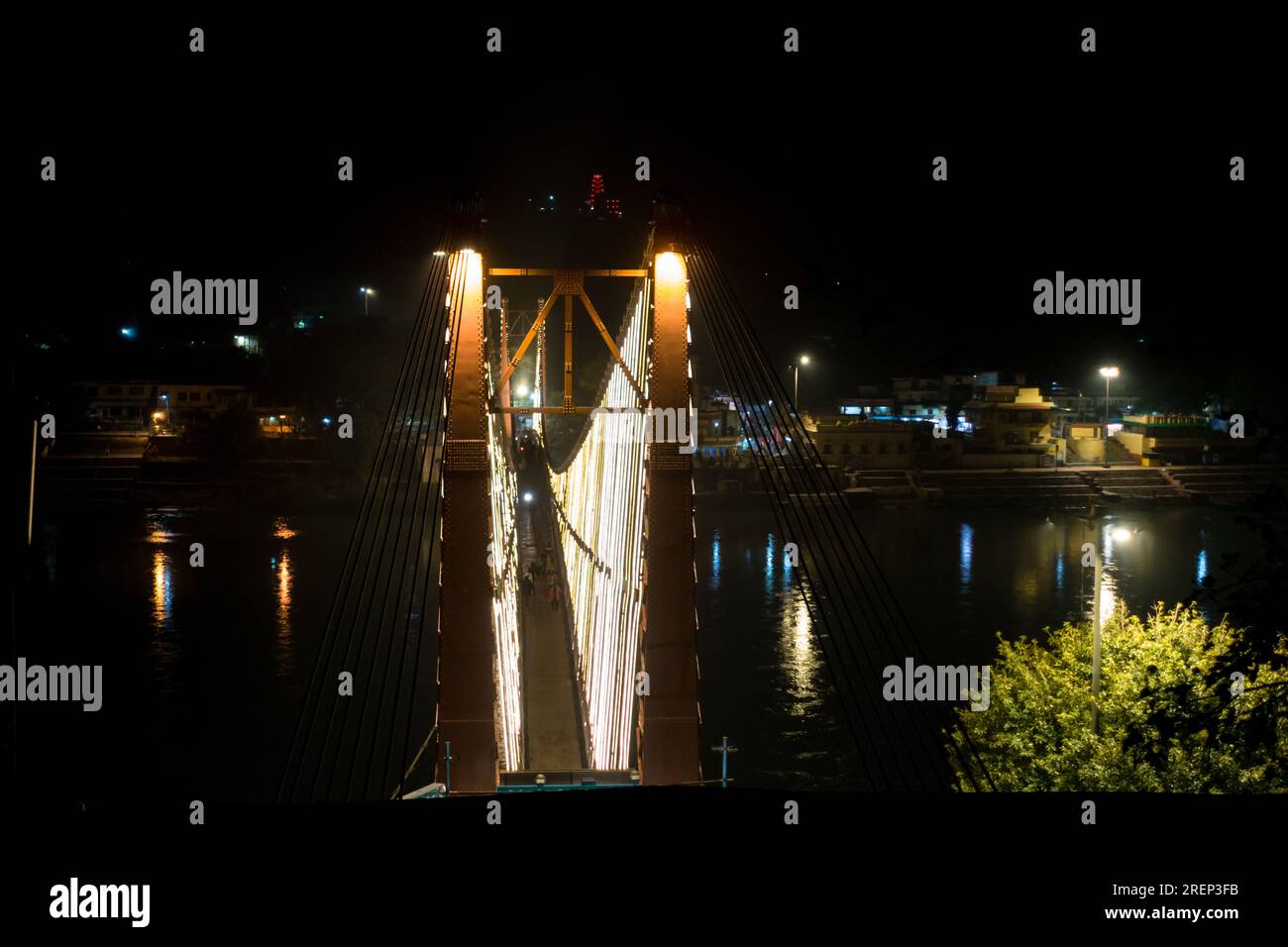Lakshman Jhula, l'ancien pont suspendu, magnifiquement éclairé par des lumières, se reflète sur le Gange à Rishikesh, en Inde. Vue nocturne enchanteresse Banque D'Images