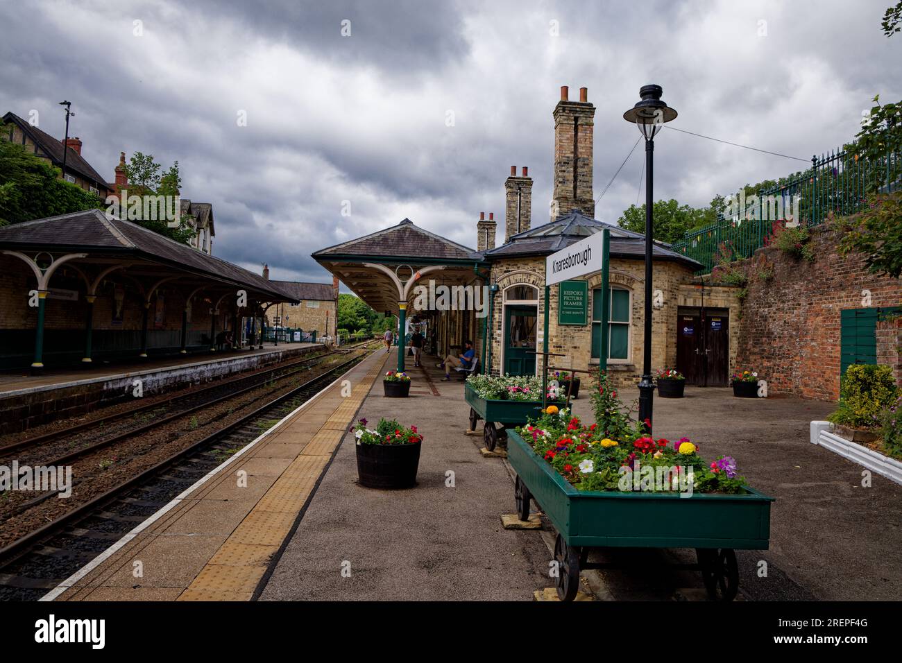 Une vue des quais et des bâtiments de la gare avec des jardinières remplies de fleurs à Knaresborough Railway Station, North Yorkshire, Angleterre. Banque D'Images