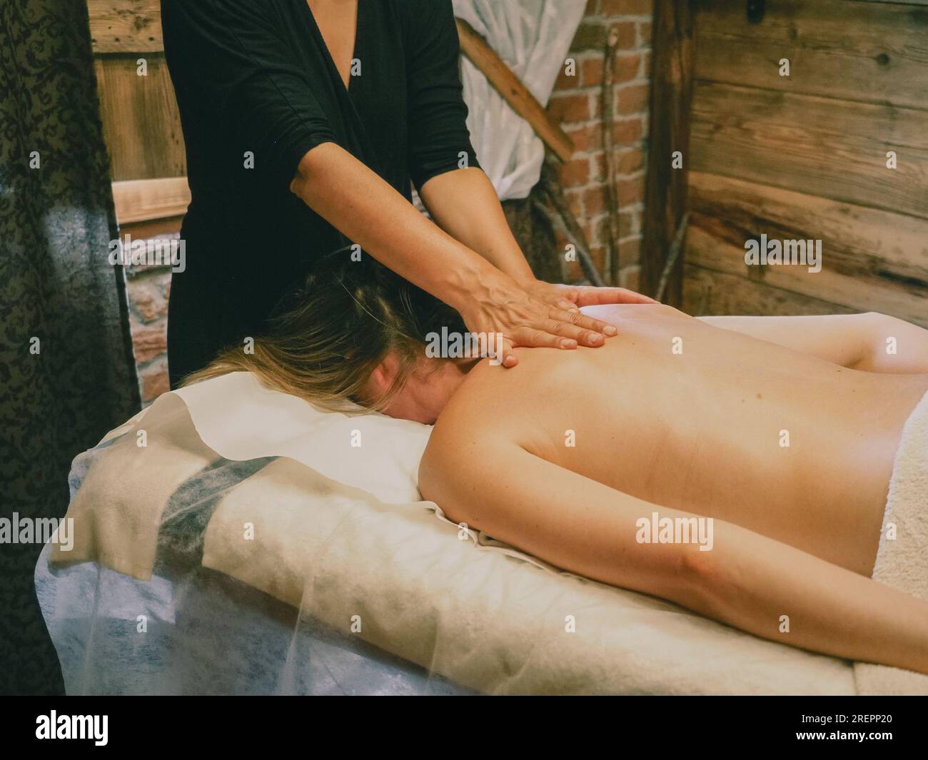 Jeune femme caucasienne apprécient le massage du dos. Un massothérapeute professionnel traite la cabine de bien-être des patientes. Relaxation, beauté, corps et visage tr Banque D'Images