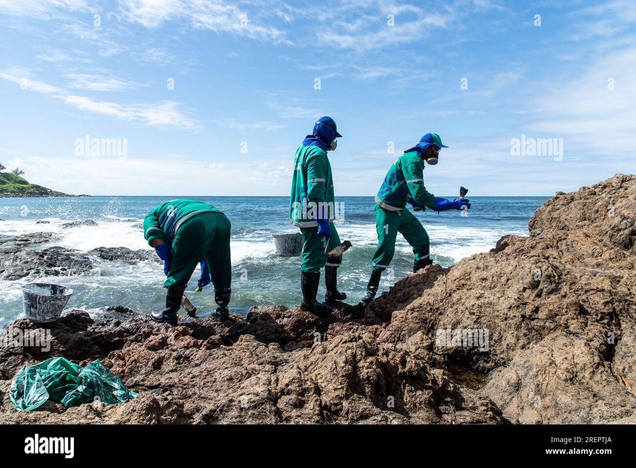 Salvador, Bahia, Brésil - 03 novembre 2019 : des responsables municipaux sont vus au sommet de rochers sur la plage de Rio Vermelho nettoyant le pétrole toxique déversé sur le Brésil Banque D'Images