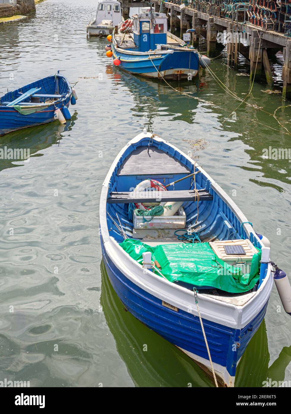 Certains bateaux sont amarrés près d'une jetée en bois. Les cordes traînent dans l'eau et les bateaux se reflètent dans l'eau. Banque D'Images