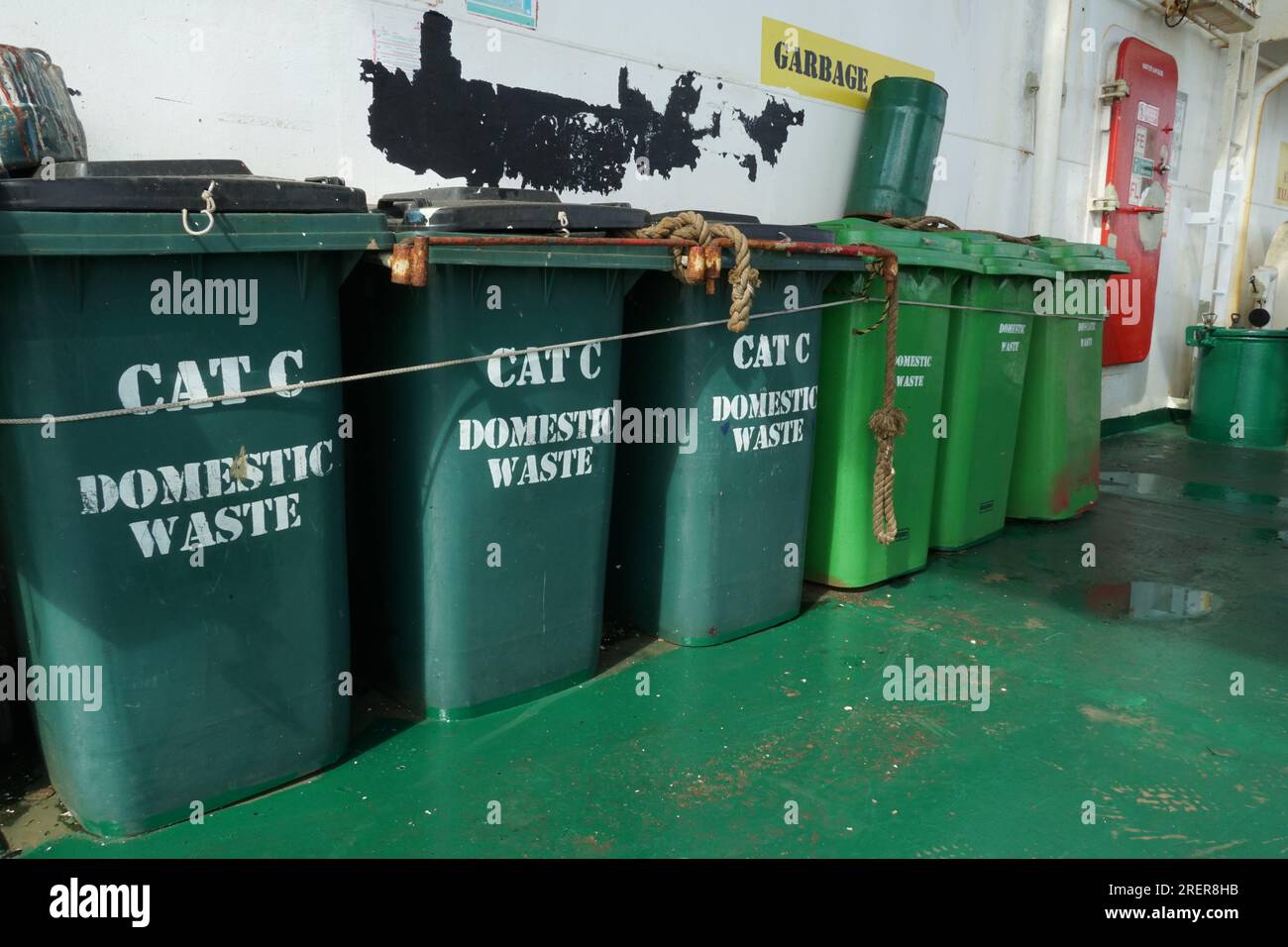 Poubelles en plastique vert pour déchets ménagers de catégorie C, fermement serrées contre les balustrades. Banque D'Images