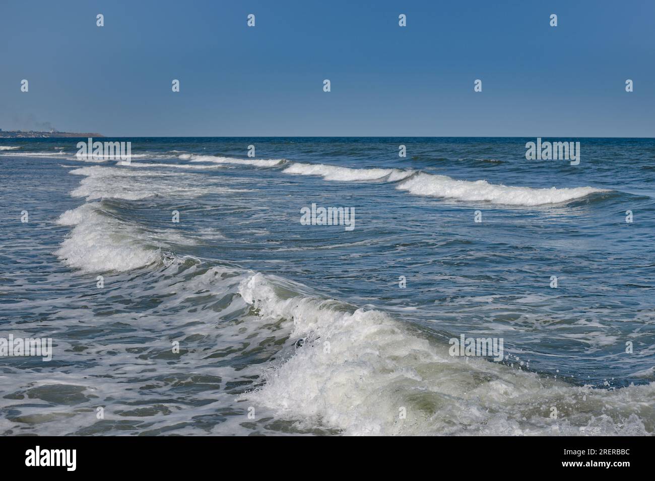 Vagues de mer roulant sur le rivage. La couleur bleue du ciel se reflète dans l'eau de la mer. Banque D'Images