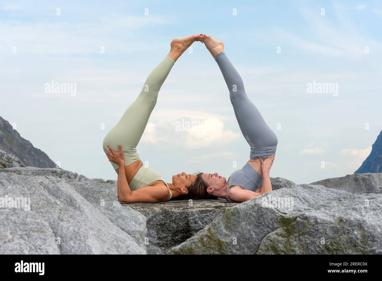 deux femmes faisant de l'acro yoga à l'extérieur, fond de montagne rocheuse. Banque D'Images