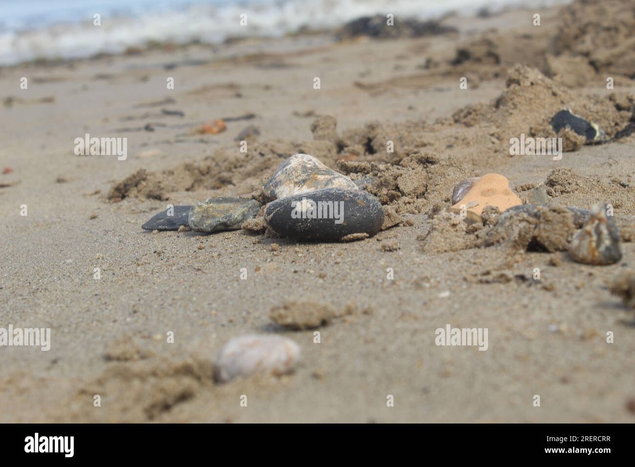 Une photo d'un rocher sur une plage de sable et l'océan en arrière-plan. Banque D'Images