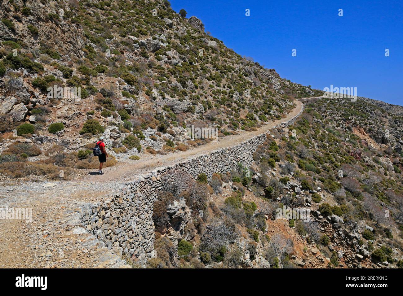 Promeneur solitaire sur le chemin de Livadia à la plage de Lethra le long du chemin de montagne rocheux, île Tilos, groupe d'îles du Dodécanèse. Grèce, juillet 2023 Banque D'Images