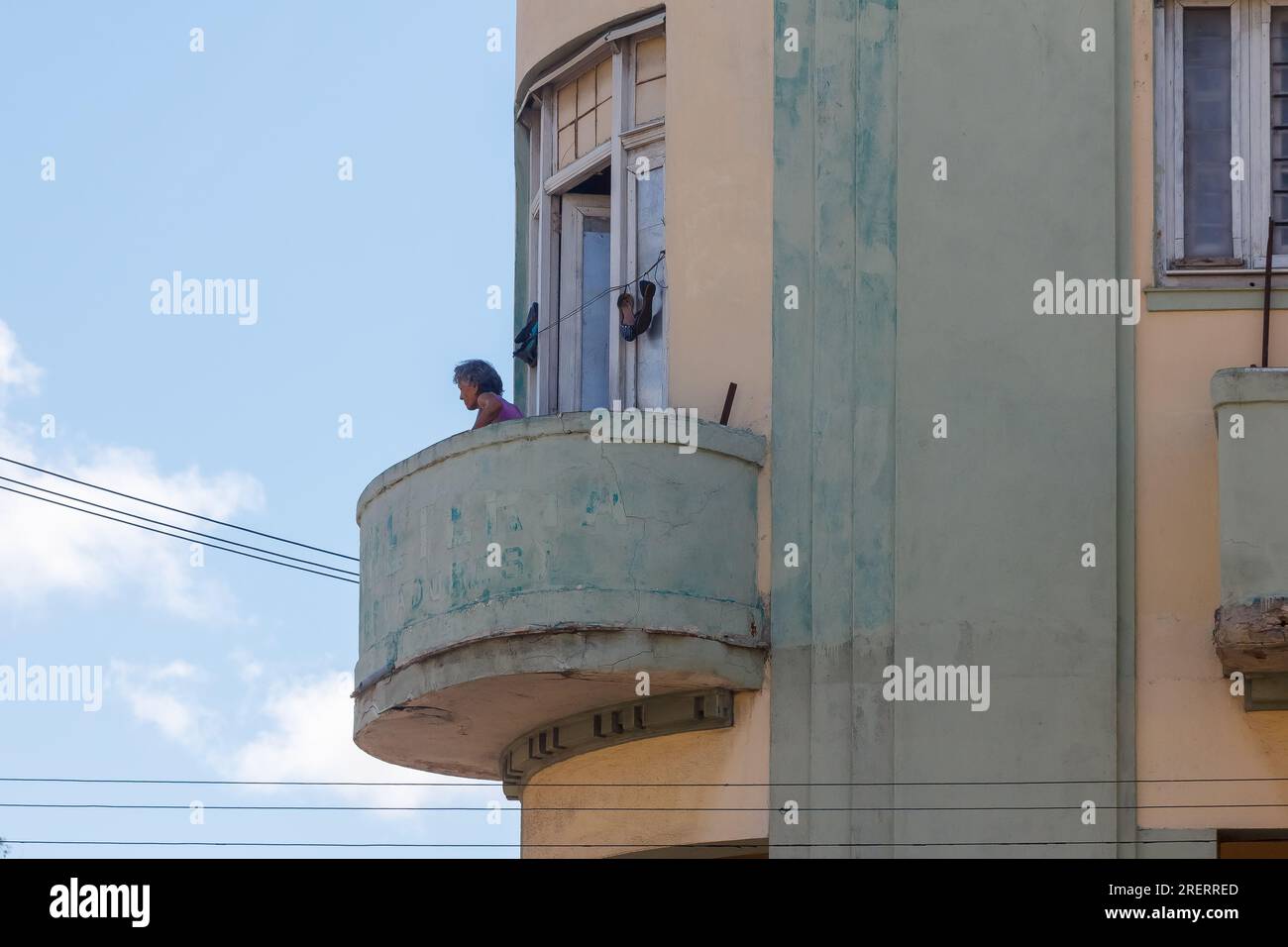 La Havane, Cuba, Une femme âgée se tient sur un balcon regardant la vie de la ville. Banque D'Images
