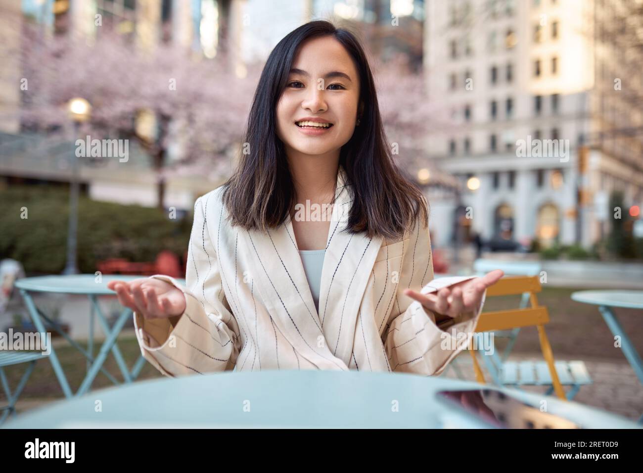 Jeune femme d'affaires asiatique heureuse parlant à la caméra à l'extérieur. Vue Web CAM Banque D'Images