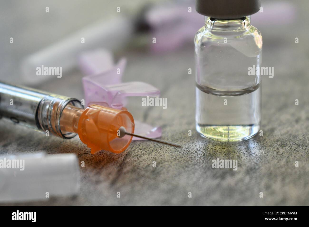 Flacon de médicament avec seringue sur une surface grise Banque D'Images