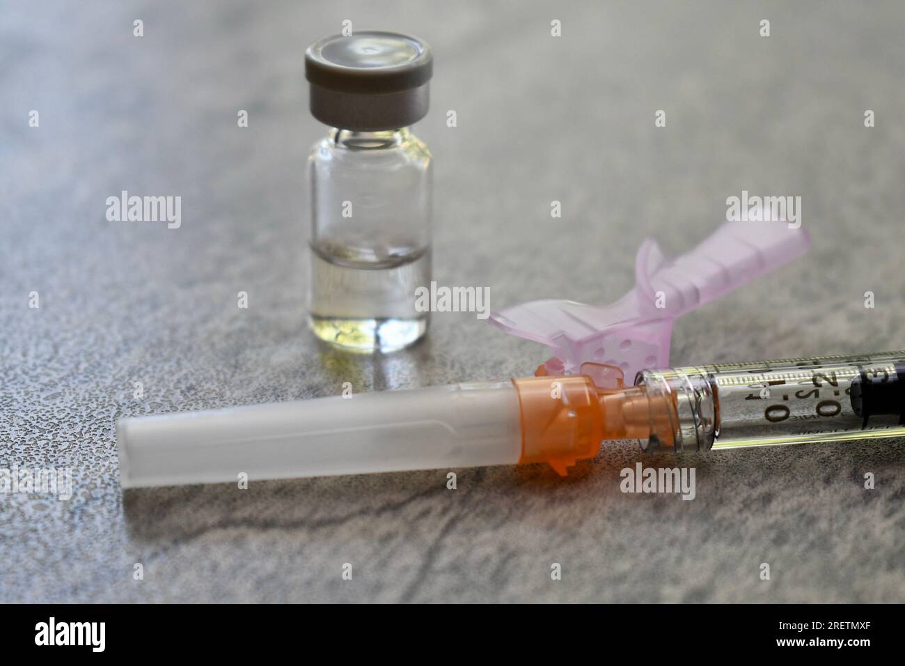 Flacon de médicament avec seringue sur une surface grise Banque D'Images