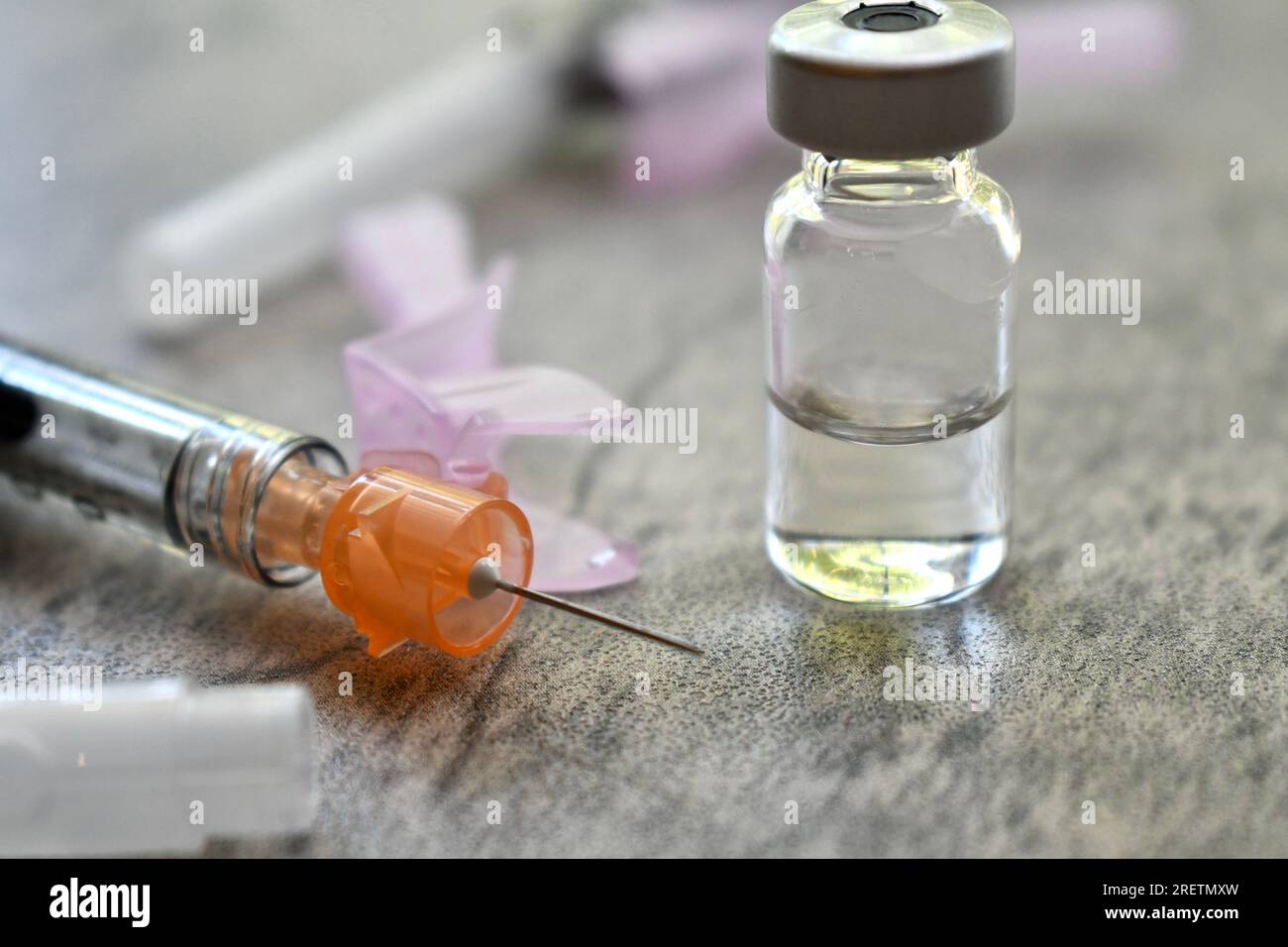Flacon de médicament avec seringue sur une surface grise Banque D'Images