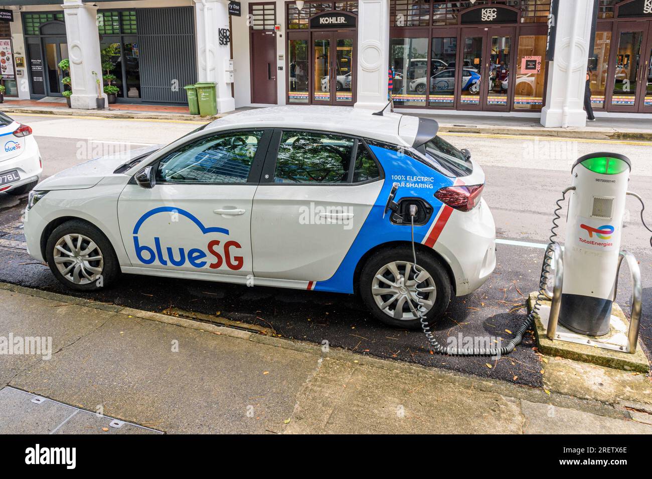 Un véhicule de partage de voiture électrique Blue SG branché à une borne de recharge à Singapour Banque D'Images