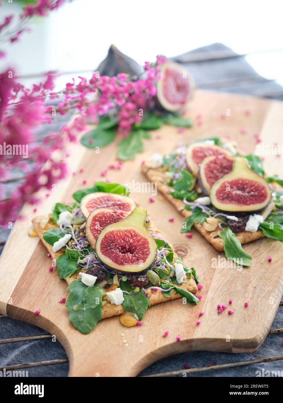 D'en haut des tranches de fruits de figue fraîches décorées de menthe verte feuilles de fromage et de salade tandis que les fleurs de couleur rose garnies et placées sur la serviette avec WO Banque D'Images