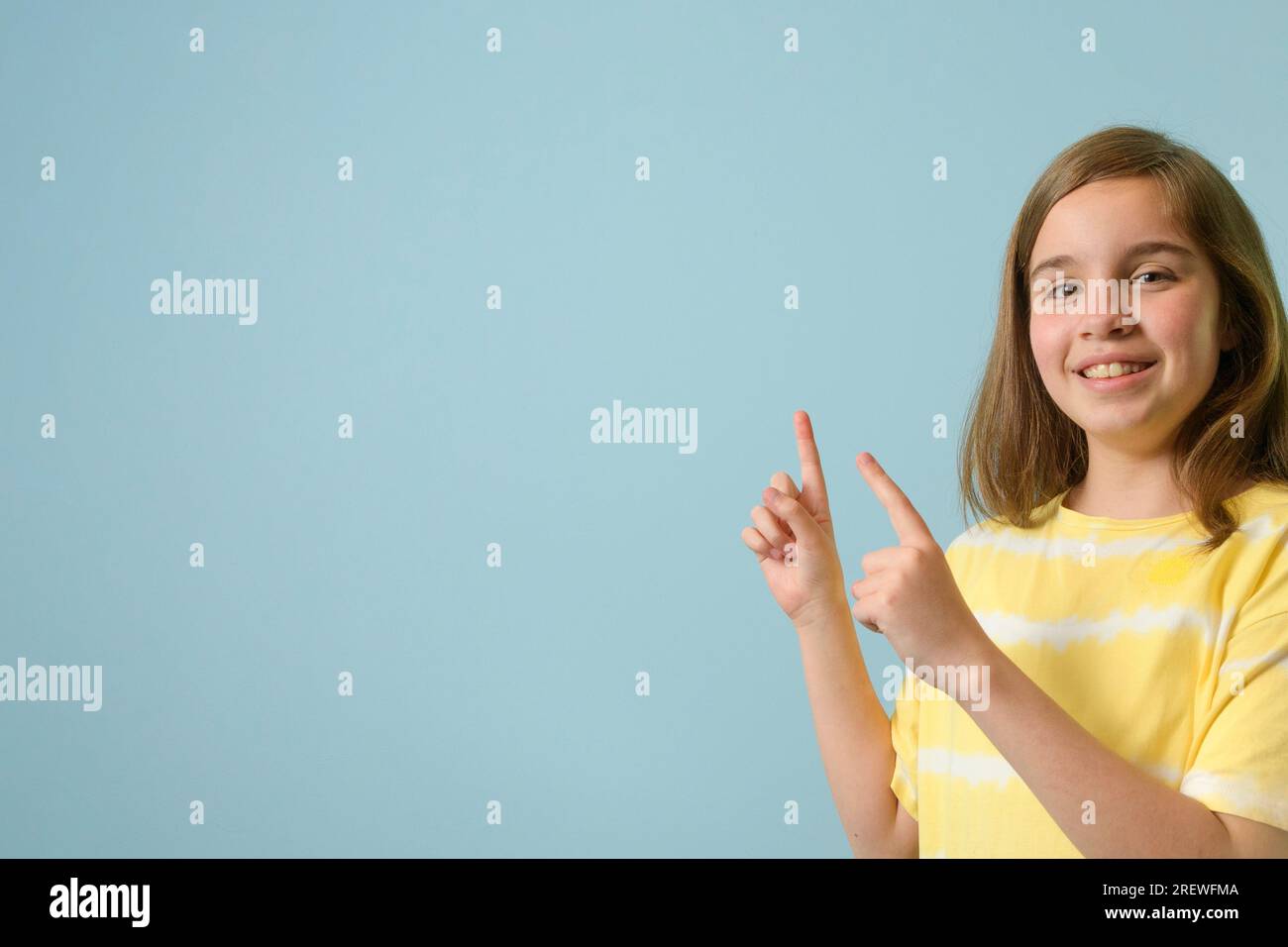 Une adolescente suggère de regarder l'espace libre pour le texte sur la gauche. Pointe les doigts vers l'espace de copie. fond vert clair Banque D'Images
