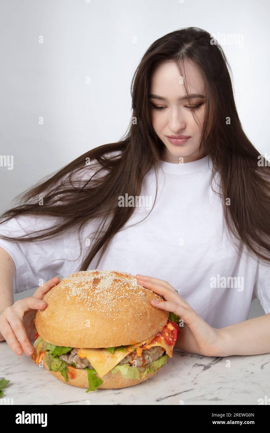 Une femme tient un gros sandwich hamburger barbecue sur le fond. Concept de restauration rapide. La fille a un énorme hamburger. Banque D'Images