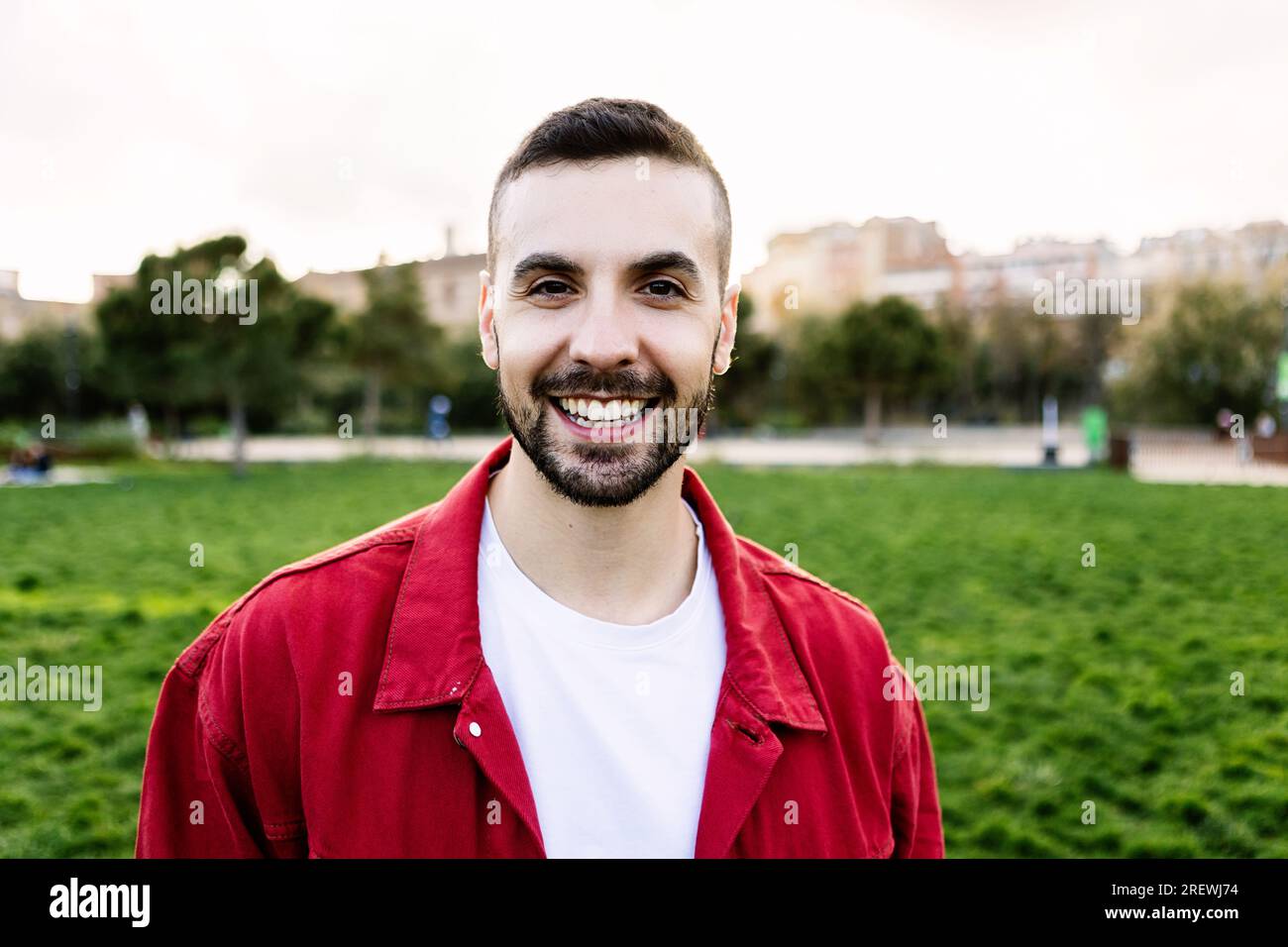 Jeune homme heureux souriant à la caméra dehors. Banque D'Images