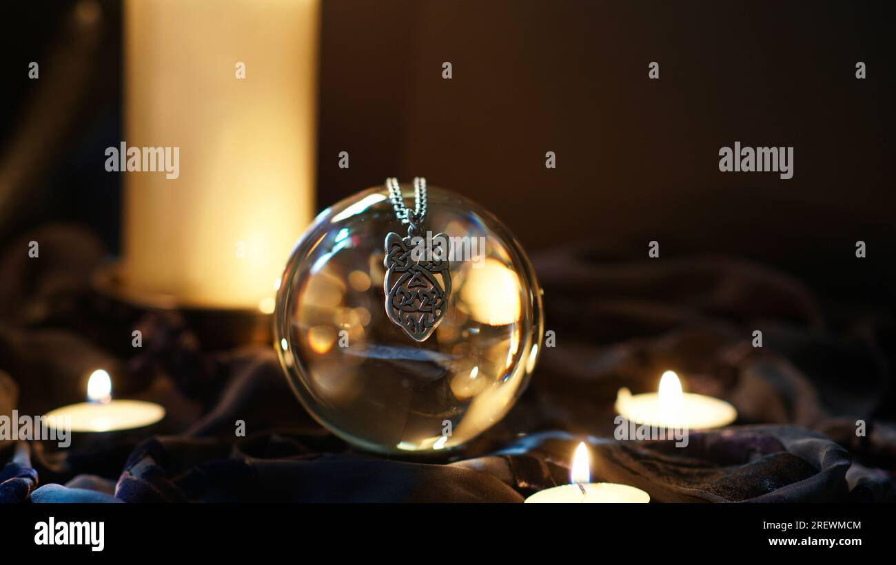 Un collier gothique suspendu au-dessus d'une boule d'objectif entourée de bougies. Banque D'Images