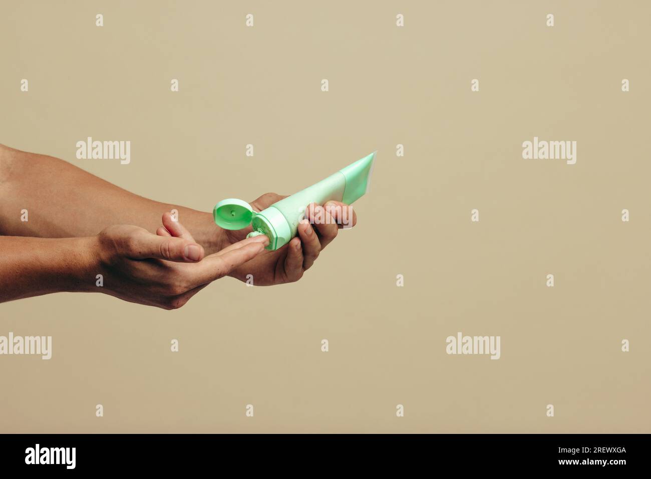 Mains masculines distribuant une crème de masque facial pour une routine de soins de la peau. Jeune homme prenant soin de sa peau avec un produit de beauté nettoyant pour maintenir son fr Banque D'Images